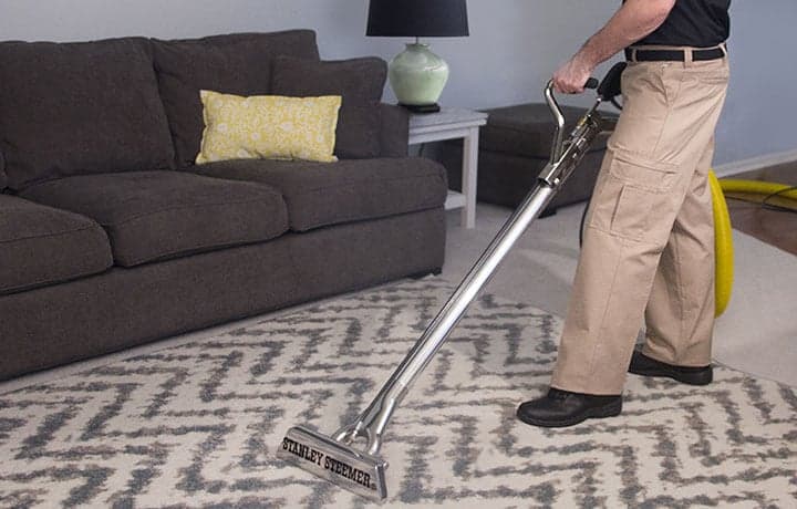 Area-Rug-Cleaning-Certified-Technician-Cleaning-Rug Stanley Steemer technician cleaning an area rug with a wand.