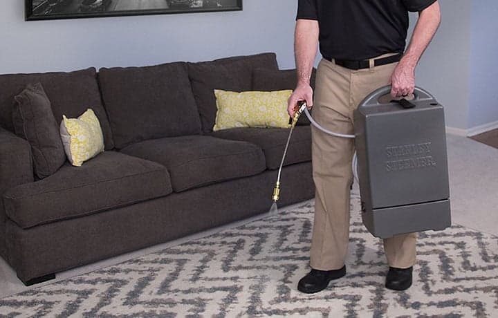 Area-Rug-Cleaning-Certified-Technician-Protecting-Rug Stanley Steemer technician spraying protector on an area rug.