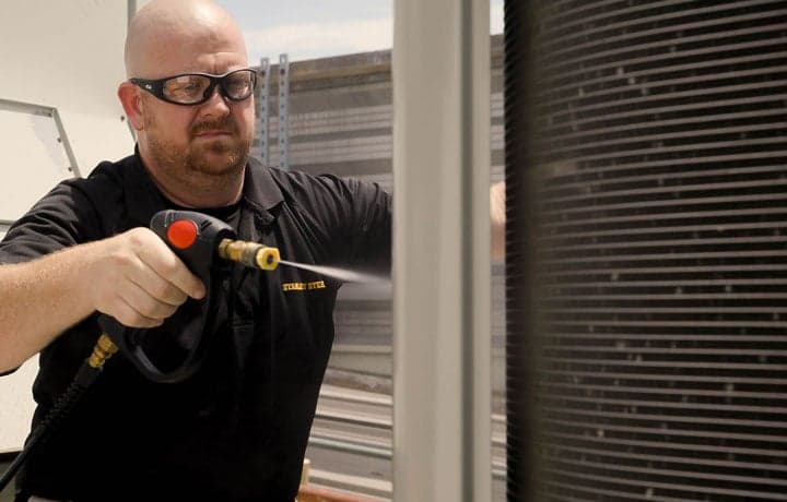 Stanley Steemer technician cleaning HVAC rooftop unit