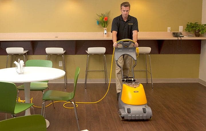 Technician performing commercial cleaning services to hardwood