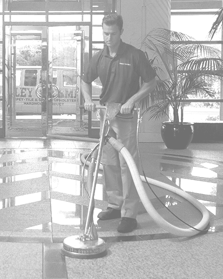 Stanley Steemer technician cleaning tile and grout Black and white image of Stanley Steemer technician deep cleaning tile and grout floors in office lobby
