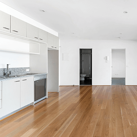 Empty apartment overlooking hardwood floors in kitchen and living space Empty apartment overlooking hardwood floors in kitchen and living space