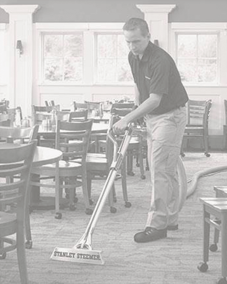 Stanley Steemer tech cleaning carpet in dining area of restaurant Stanley Steemer technician cleaning carpet in dining area of restaurant