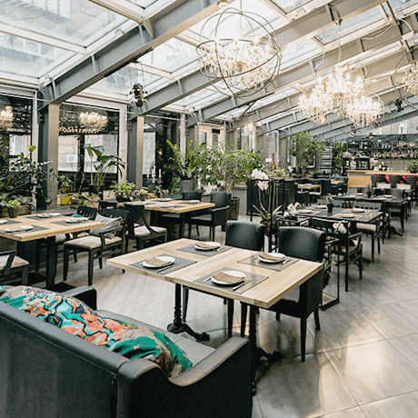 Restaurant with seating and natural light Restaurant with natural lighting, wood tables, and plants
