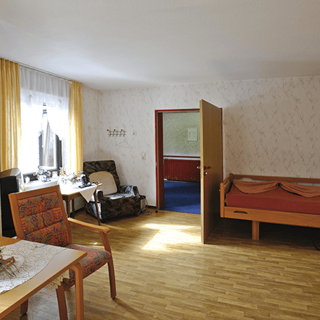 Nursing home bedroom with laminate floors and upholstered furniture