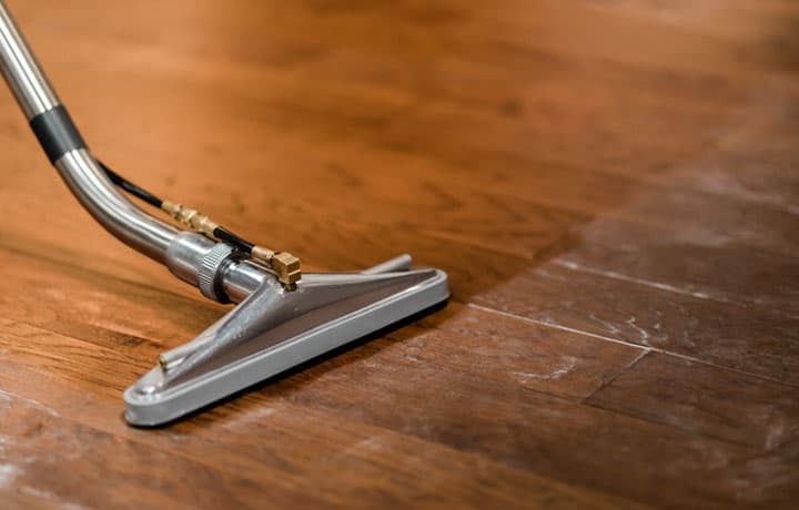 A Professional Cleaning Vacuum in the Middle of Cleaning a Dirty Vinyl Plank Floor A professional cleaning vacuum in the middle of cleaning a dirty vinyl plank floor