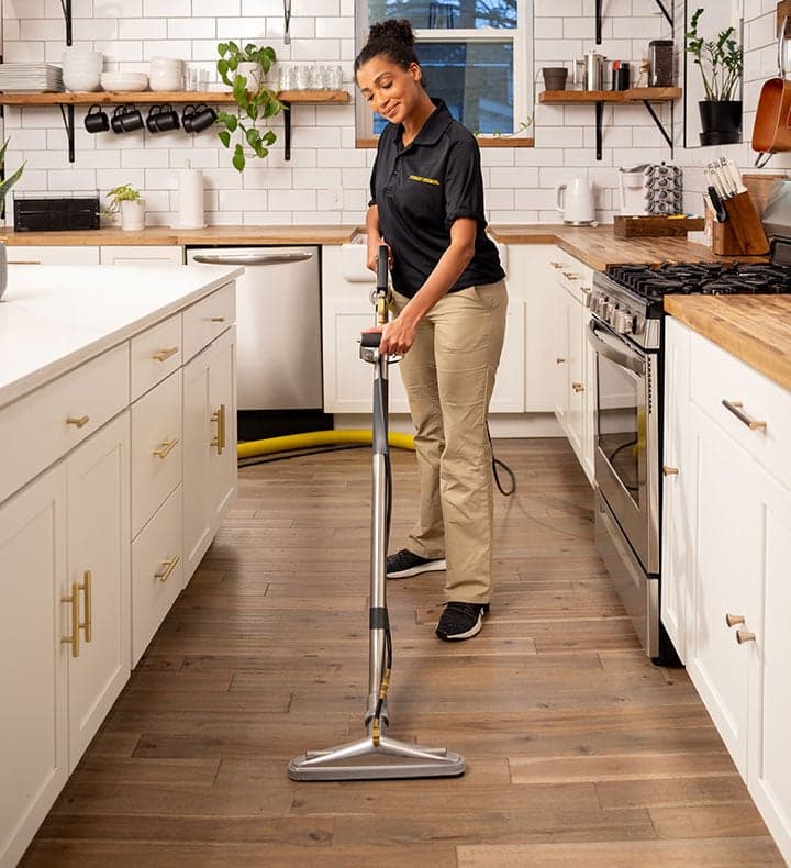 A Stanley Steemer Technician Pulls a Cleaning Wand Across Luxury Vinyl Plank Flooring in a Country-Style Kitchen A Stanley Steemer technician pulls a cleaning wand across luxury vinyl plank flooring in a country-style kitchen