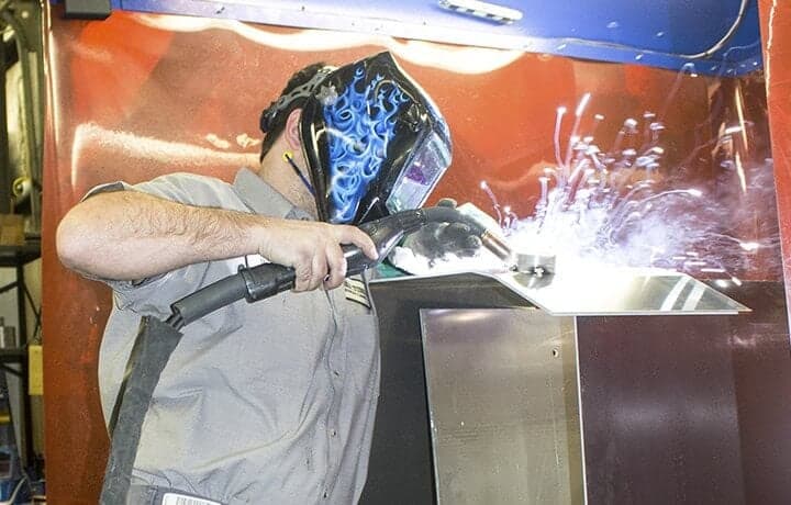Made-In-America-Worker Metal smith worker with a face mask on and sparks flying.