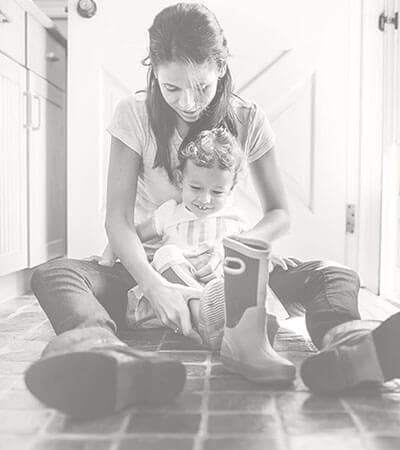 Mother and daughter sitting on a natural stone floor in their kitchen. 