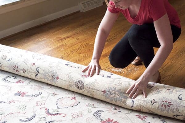 Rug-On-Hardwood Woman moving rug to clean hardwood