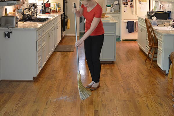 Homeowner sweeping hardwood floors
