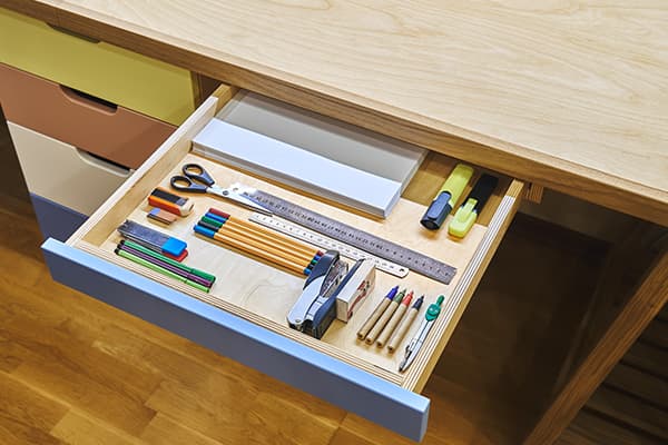 wooden desk with school supplies in drawer