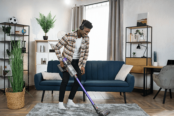 man vacuuming area rug in living room