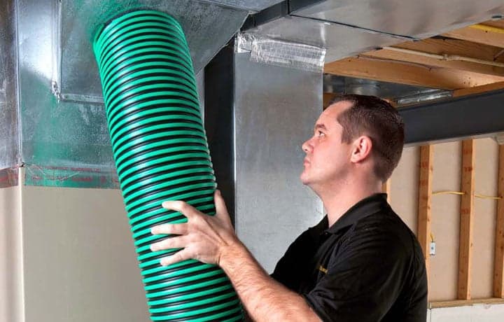 Stanley Steemer technician vacuuming air duct vent