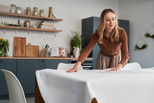 blond woman smoothing table cloth in springtime dining room
