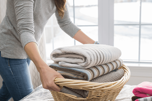 Work out Clean Checklist Blog Image Homeowner carrying a load of clean, folded laundry