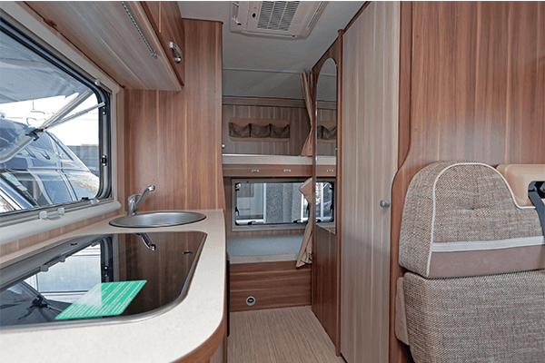 RV Kitchen, Seating, and Flooring RV living space showing the kitchenette to the side and seating. Wood paneling are the walls.