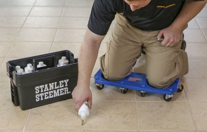 Tile-and-Grout-Sealing Stanley Steemer technician sealing the grout lines on a tile floor.